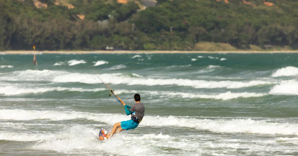 Un kitesurfer profitant d'une balade passionnante sur des vagues océaniques agitées près d'une côte pittoresque.
