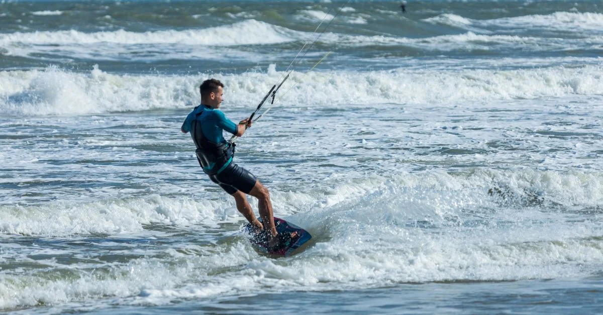 Une scène de kitesurf passionnante capturant un homme chevauchant les vagues de l'océan en été.