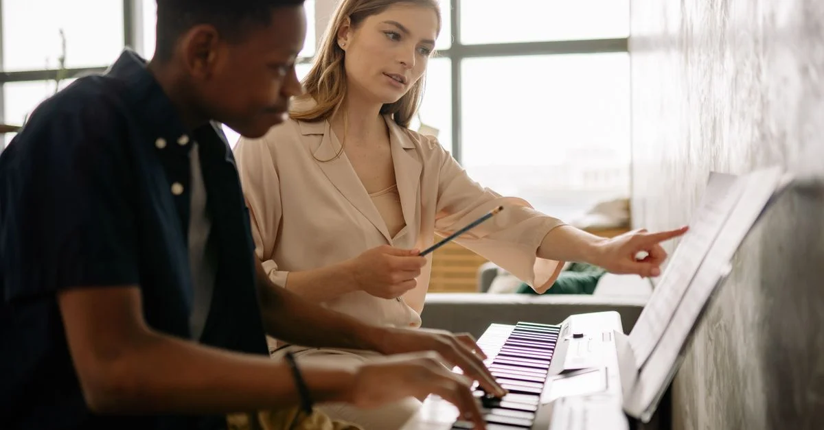 Un adolescent apprenant le piano avec un professeur à domicile, se concentrant sur des notes de musique.