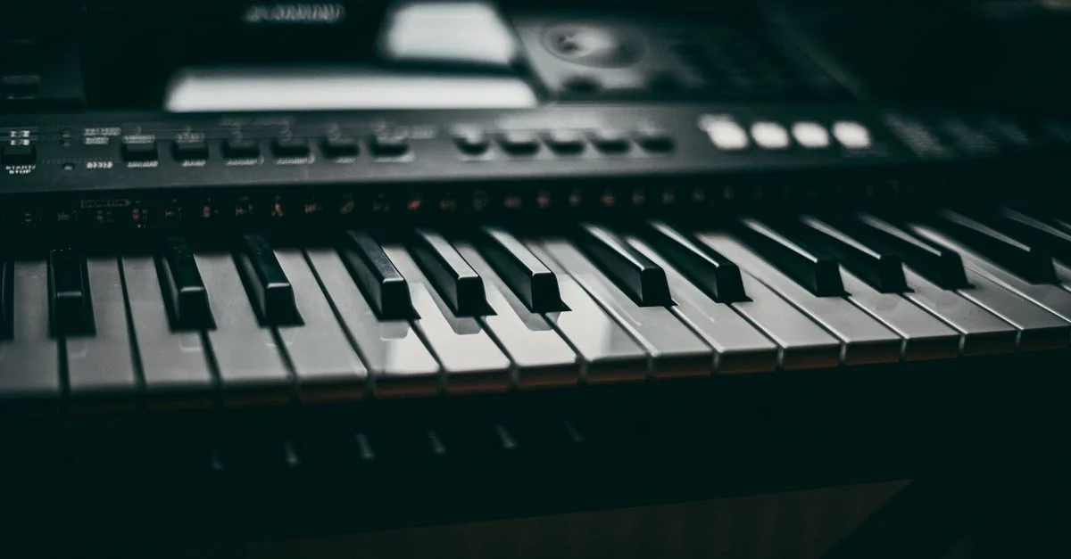 Gros plan détaillé des touches de piano sur un clavier électronique dans une ambiance tamisée.