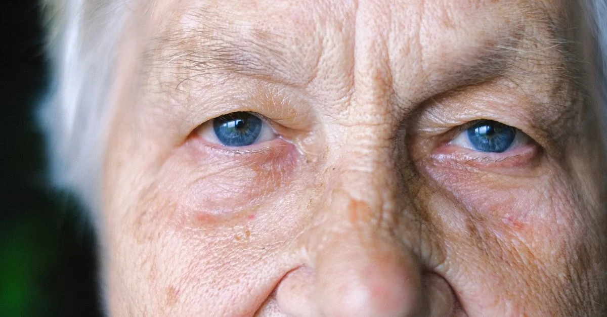 Gros plan détaillé du visage d'une femme âgée mettant en valeur ses yeux bleus et ses rides.