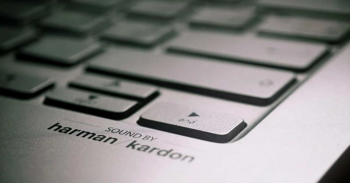 Vue détaillée du clavier d'un ordinateur portable avec l'étiquette du haut-parleur Harman Kardon, mettant en évidence ses caractéristiques audio haut de gamme.